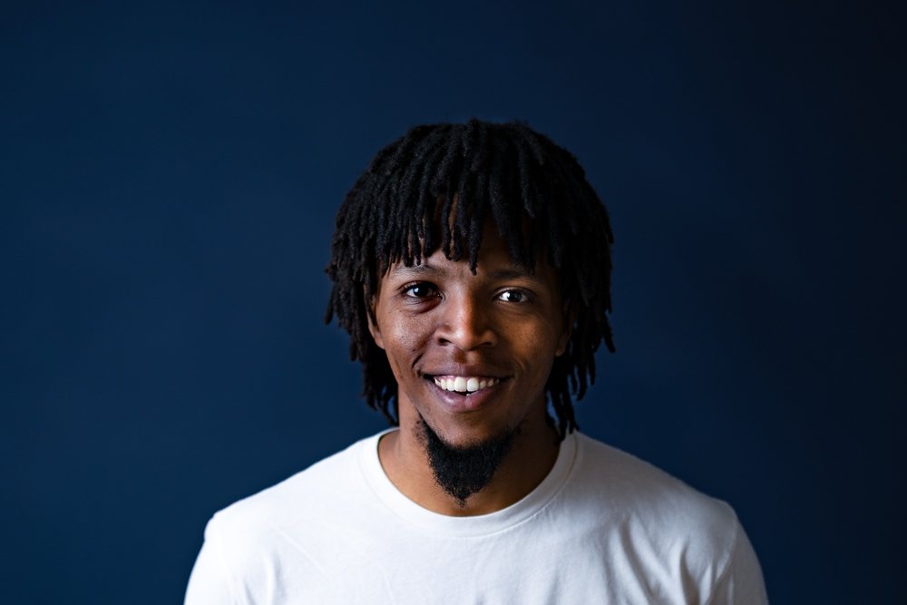 Mmuso, founder of BOLO Trends, smiling in a white t-shirt against a navy wall